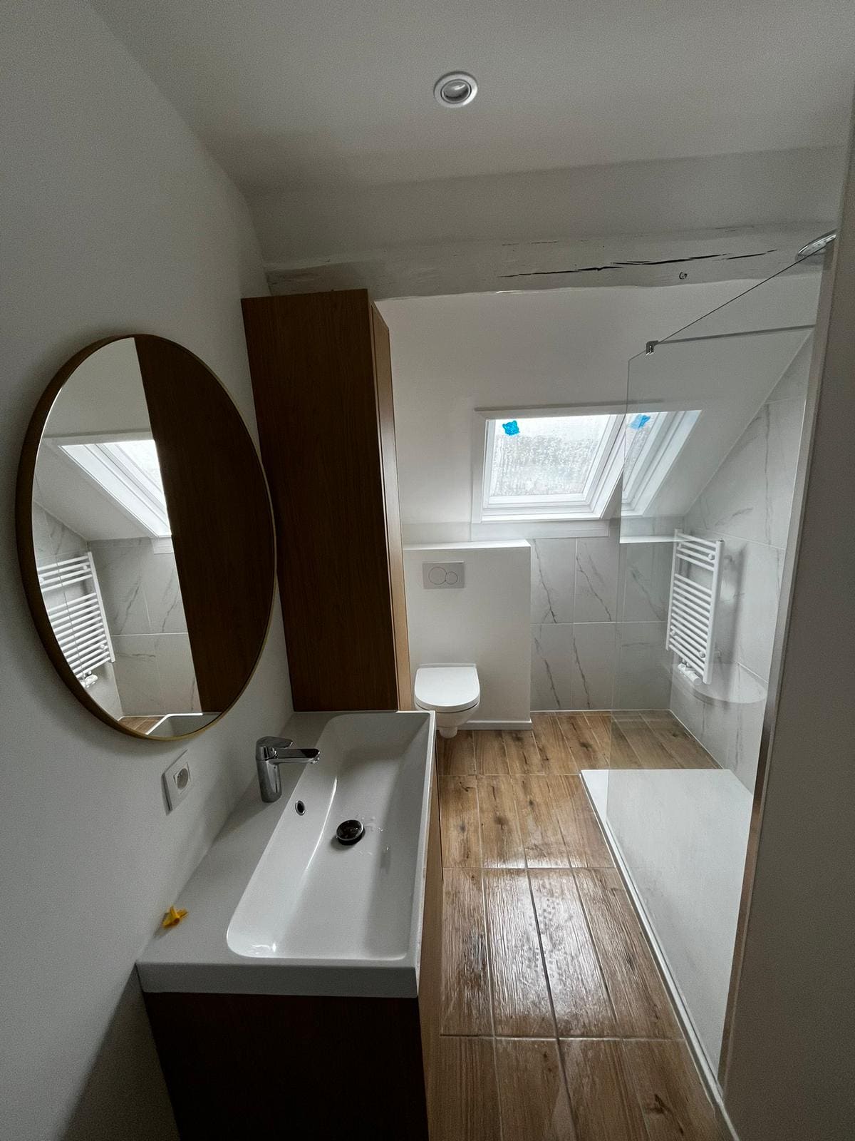 Salle de bain sous toiture avec miroir rond
